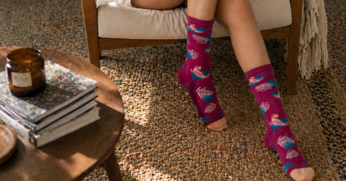 גרבי WildSock בצבע בורדו עם ציור קקדו, ישיבה בכורסה בבית בערב חורף