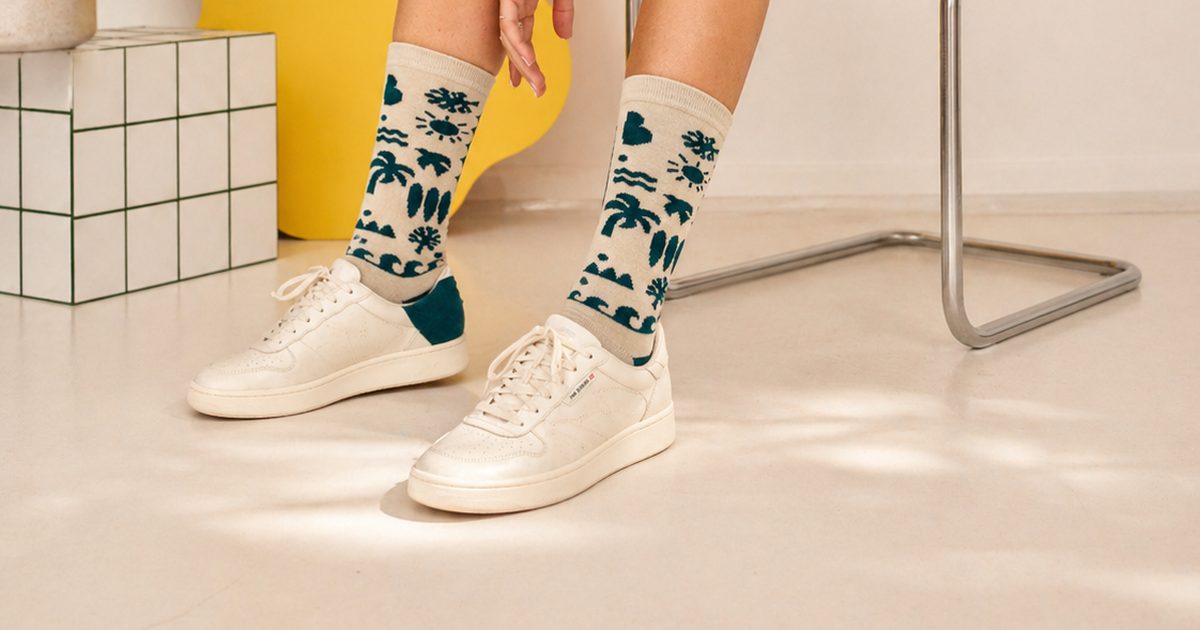 נערה בסוודר מפוספס יושבת על כיסא עם גרבי WildSock בצבע שמנת ודוגמה ירוקה